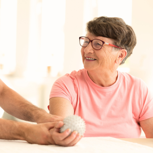 Older woman smiling, holding ball, stroke recovery